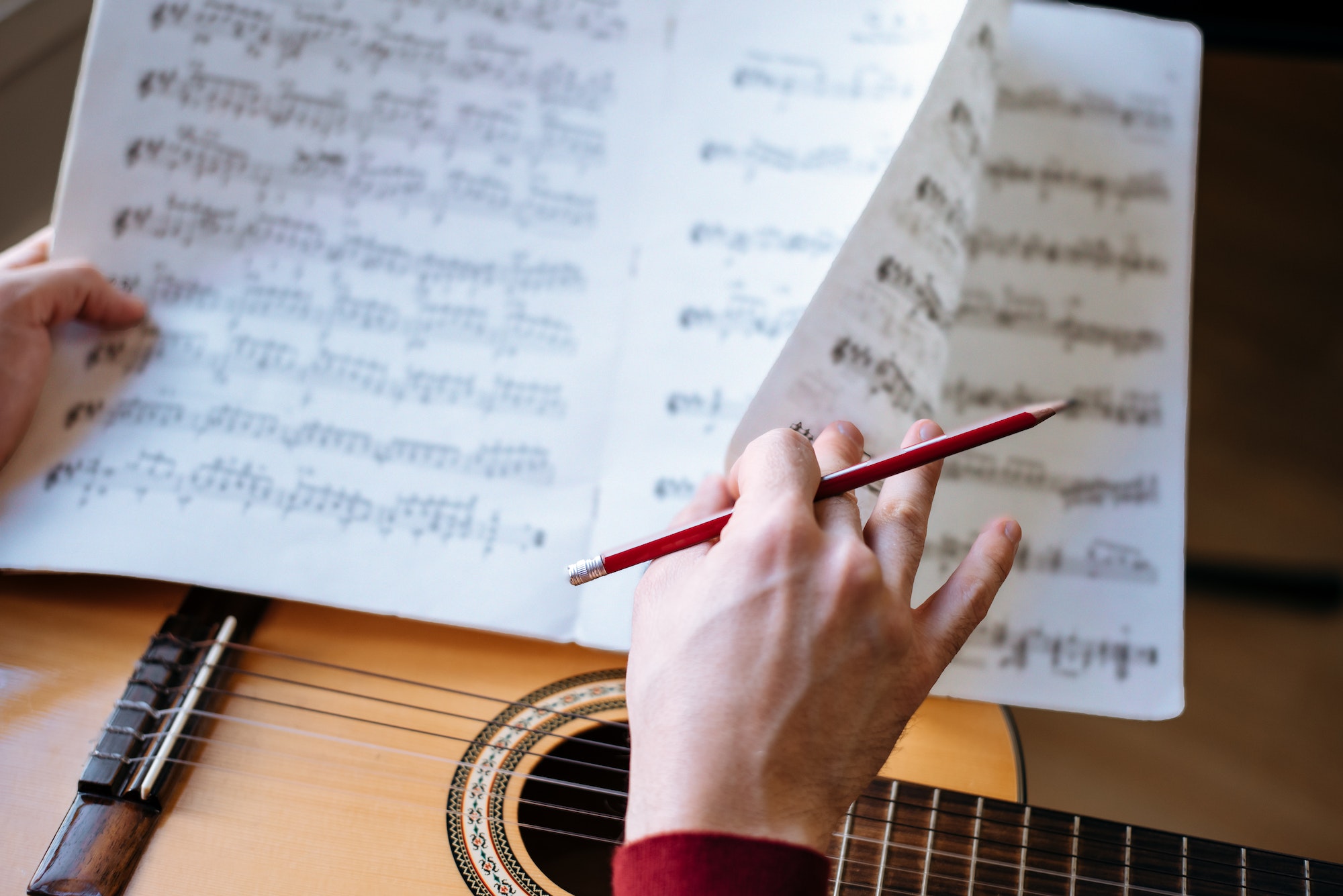 Man hands with sheet music playing guitar